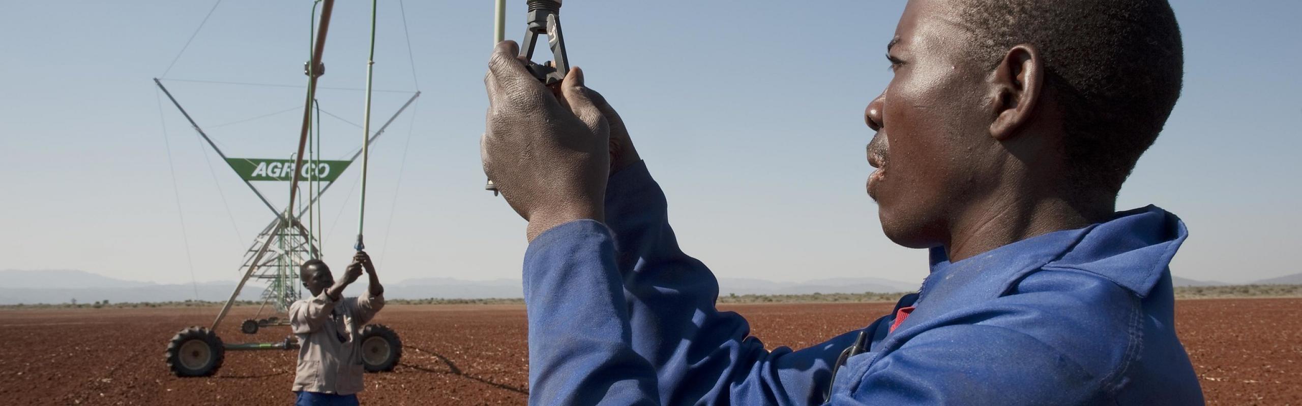 Two men prepare irrigation equipment on a field  in Strydkraal, South Africa