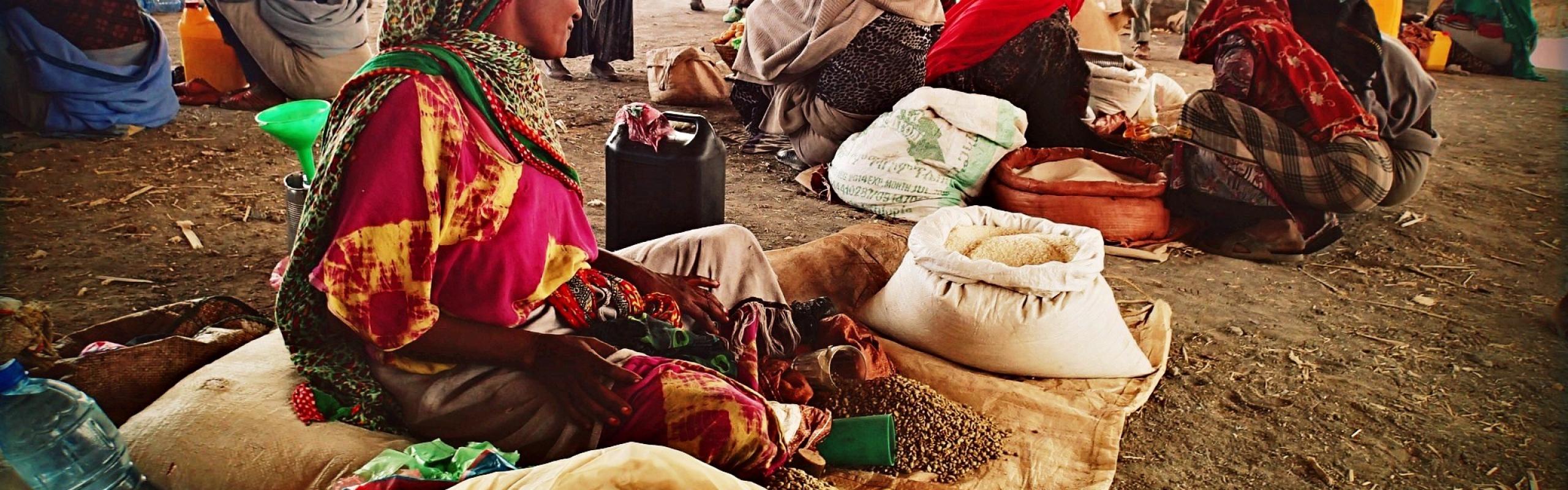 Woman sits among cloth sacks of grain in a market in Ethiopia