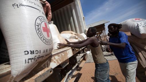 Community members at the Nifasha IDP camp in North Darfur unload bags of sorghum from a WFP truck.