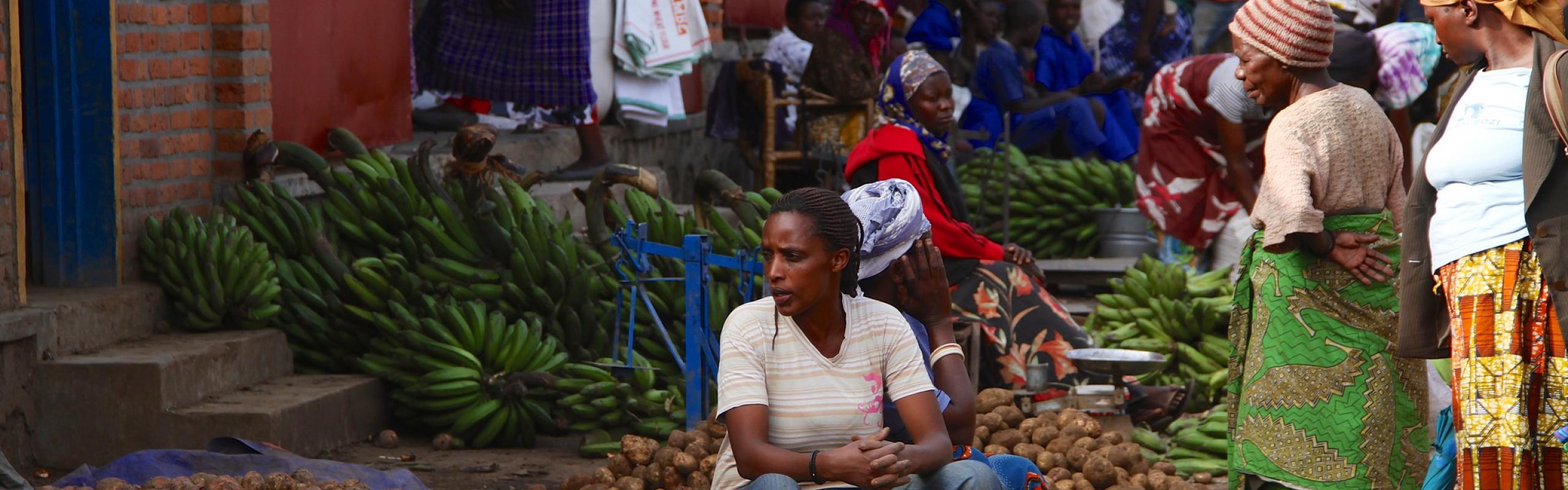 Vendors sitting among piles of potatoes and bananas in a marketplace, Musanze, Rwanda.